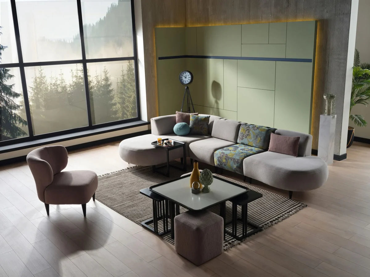 An enveloping pearl-gray corner sofa, layered with plush cloud-stitched cushions. Resting beneath a wide, light-drenched window, flanked by a glinting mirror of quiet elegance. A sanctuary shaped by softness, serenity, and sacred design.